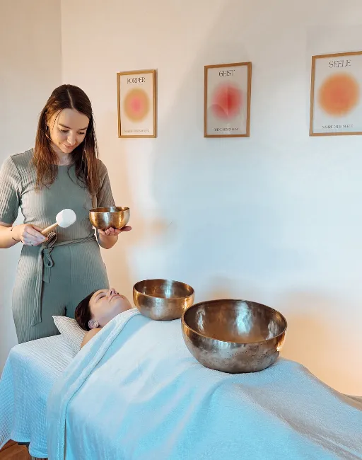 Therapeutin Eva-Maria Prey führt Heilmassage mit Klangschalen bei Patientin zur Entspannung durch